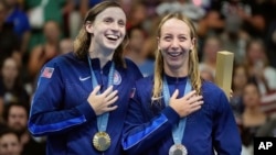 FILE - United States' Katie Ledecky, left, and teammate and Paige Madden celebrate with the gold and bronze medal for women's 800-meter freestyle the at the Summer Olympics in Nanterre, France, Aug. 3, 2024.