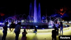 People enjoy a fountain lit in colored lights after a nationwide power outage, in Valencia, Venezuela, Aug. 30, 2024. 