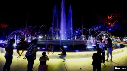 People enjoy a fountain lit in colored lights after a nationwide power outage, in Valencia, Venezuela, Aug. 30, 2024. 