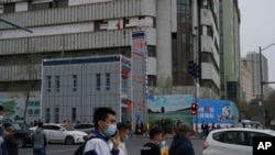 FILE - People walk past a police station in Urumqi, the capital of China's far west Xinjiang region, on April 21, 2021. Prominent Uyghur scholar Rahile Dawut, not pictured, reportedly has been sentenced to life in prison for "endangering state security." 