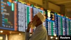 FILE - A stock broker reacts while monitoring the market on the electronic board displaying share prices during trading session at the Pakistan Stock Exchange, in Karachi, Pakistan, July 3, 2023.