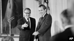 FILE - Secretary of State Henry Kissinger, left, gestures to the audience in the East Room of the White House, Sept. 22, 1973, as President Richard Nixon watches, in Washington. Kissinger had just been sworn in as the 56th secretary of state.