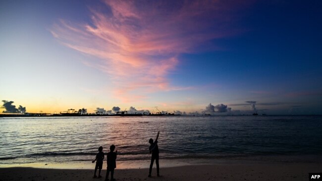 FILE - People walk along a beach at Vilimalé island in the the Maldives on Nov. 15, 2023.