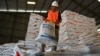 Seorang pekerja menangani karung beras yang diimpor dari Thailand di gudang Biro Logistik Indonesia (BULOG) di Lambaro, provinsi Aceh, 16 Mei 2023. (CHAIDEER MAHYUDDIN / AFP)