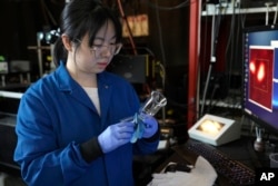 Naixin Qian, ahli kimia fisik Columbia, mendemonstrasikan peralatan penyaringan kaca yang digunakan untuk menguji sampel air untuk nanoplastik, potongan plastik mikroskopis, di New York, Senin, 8 Januari 2024. (AP/Mary Conlon)