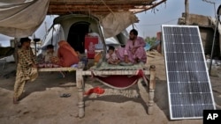 A flood victim and his family eat rice next to a solar panel used for electricity in Ismail Khan Khoso village in Sohbatpur, a district of Pakistan's Baluchistan province, May 18, 2023.