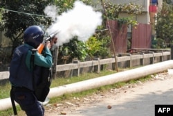 A policeman fires tear gas to disperse a mob along a street during a protest in Chittagong, Bangladesh, Jan. 7, 2024.