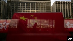 A pedestrian walking through a footbridge is silhouetted as Chinese and Hong Kong flags are strung to mark the 26th anniversary of the city's handover from Britain to China in Hong Kong, on June 27, 2023. 