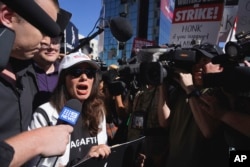 SAG-AFTRA president Fran Drescher, left, speaks with reporters as she takes part in a rally by striking writers and actors outside Netflix studio in Los Angeles, July 14, 2023.