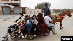 Palestinians fleeing north Gaza ride a horse-drawn cart as they move southward, as Israeli tanks roll deeper into the enclave, in the central Gaza Strip, Nov. 12, 2023.