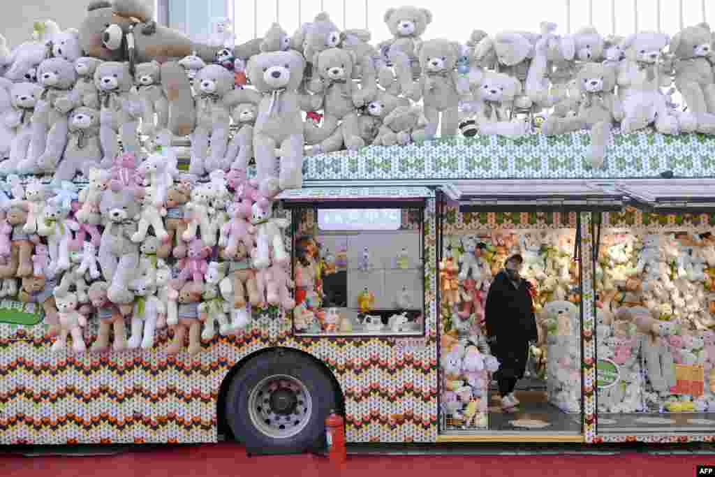 A woman is seen inside a toy shop converted from a trailer along a business street in Beijing.