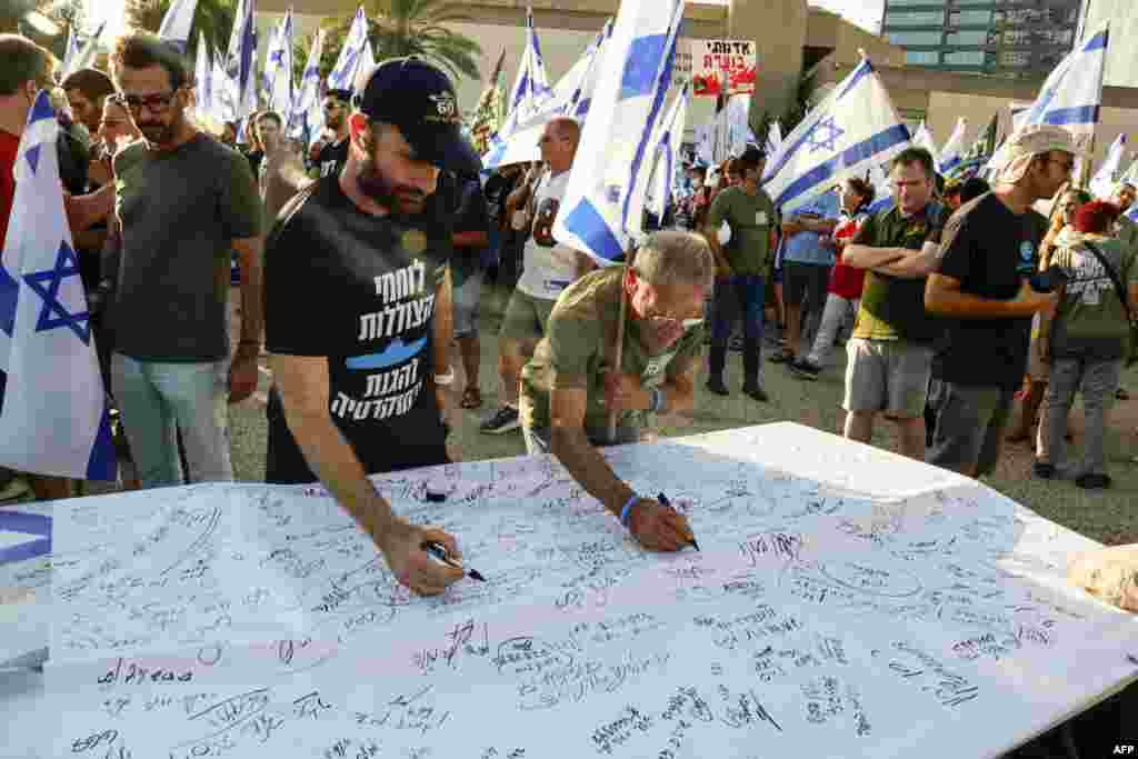 Israeli military reservists sign a declaration announcing the suspension of their voluntary reserve duty, to protest the government&#39;s judicial overhaul bill, in Tel Aviv.