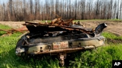 FILE - A scorched car rests in the yard of a home destroyed by a wildfire in the East Prairie Metis Settlement, Alberta, July 4, 2023. 