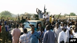 FILE - Supporters and members of the Sudanese armed popular resistance, which backs the army, raise weapons on a pick up truck during a meeting with the city's governor in Gedaref, Sudan, on Jan.16, 2024 amid the ongoing conflict in Sudan between the army and paramilitaries.