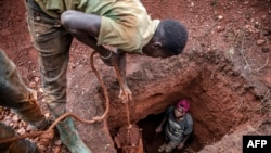 FILE - Tanzanian miners extract soil to look for gold at an open-pit gold mine in Nyarugusu, Geita Region, May 27, 2022.