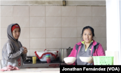 Ali Fernández (izquierda), una migrante venezolana de 28 años, y una migrante mexicana (derecha) sirven el desayuno en el albergue El Buen Samaritano de Ciudad Juárez, México, el 24 de enero de 2024.