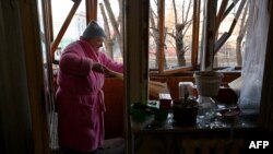 A woman sweeps broken window glass in her flat after the explosion of a downed Russian drone in a yard among residential buildings in Kyiv, Ukraine, on Nov. 25, 2023. 