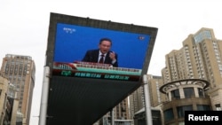 FILE - A giant screen displays a live broadcast of Chinese Premier Li Qiang speaking at a news conference following the closing session of the National People's Congress, in Beijing, China, March 13, 2023. 