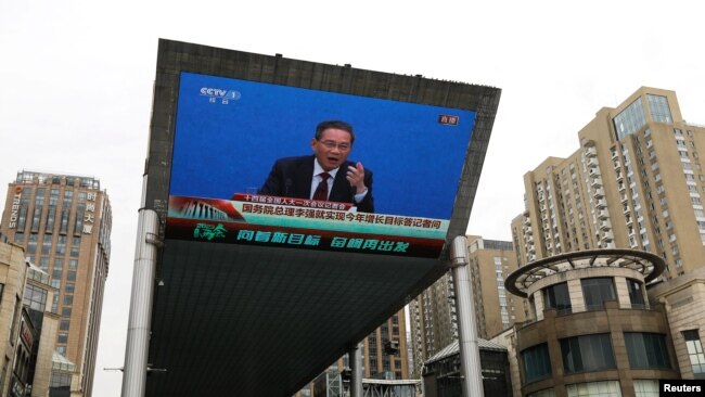 FILE - A giant screen displays a live broadcast of Chinese Premier Li Qiang speaking at a news conference following the closing session of the National People's Congress, in Beijing, China, March 13, 2023.