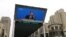 FILE - A giant screen displays a live broadcast of Chinese Premier Li Qiang speaking at a news conference following the closing session of the National People's Congress, in Beijing, China, March 13, 2023. 