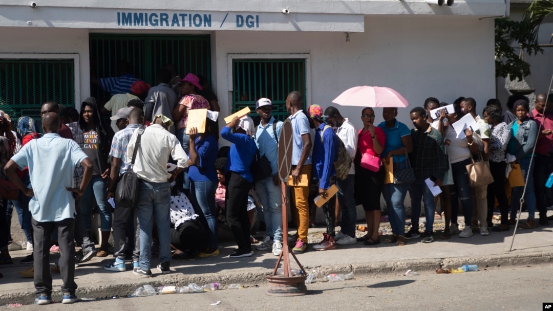 FILE - Haitians wait outside an immigration office to apply for a passport, in Port-au-Prince, Haiti, Jan. 10, 2023. President Joe Biden had announced an expansion of humanitarian parole on Jan. 5 for Cubans, Haitians, Venezuelans and Nicaraguans.