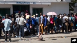 FILE - Haitians wait outside an immigration office to apply for a passport, in Port-au-Prince, Haiti, Jan. 10, 2023. President Joe Biden had announced an expansion of humanitarian parole on Jan. 5 for Cubans, Haitians, Venezuelans and Nicaraguans.