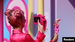 A fan takes a photo of a Barbie doll at the world premiere of the film "Barbie" in Los Angeles, California, July 9, 2023. 