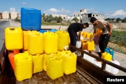 Palestinians gather to collect water, amid shortages of drinking water, as the Israeli-Palestinian conflict continues, in Khan Younis in the southern Gaza Strip, Oct.15, 2023.