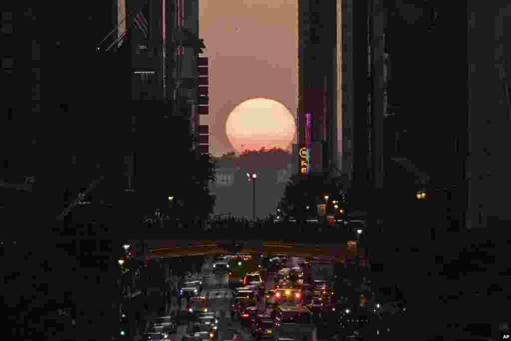 The sun sets as seen between buildings along 42nd Street in New York during a phenomenon known as Manhattanhenge, May 30, 2023.