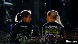 Members of the fire department speak as they work following an incident in which several individuals were killed on Friday night when a man randomly stabbed passers-by with a knife at a city festival, in Solingen, Germany, Aug. 24, 2024.