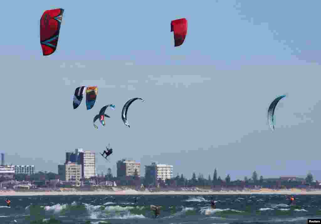 People kitesurf on a sunny day at Bloubergstrand beach in Cape Town, South Africa.