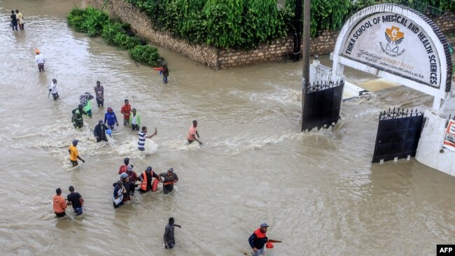 Pedestrians wade through a flooded street following heavy rains at Kiembeni district in Mombasa, Kenya, Nov. 17, 2023.