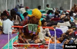 Laxmi Kumar places her three year old son Arvind inside a cradle at a temporary shelter for people evacuated from Kandla port, before the arrival of cyclone Biparjoy, in Gandhidham, in the western state of Gujarat, India, June 13, 2023.