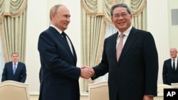 FILE - Russian President Vladimir Putin, left, and Chinese Premier Li Qiang shake hands during their meeting at the Kremlin in Moscow, Russia, Aug. 21, 2024.