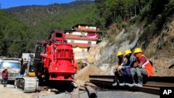 Rescuers rest at the site of an under-construction road tunnel that collapsed in Silkyara in the northern Indian state of Uttarakhand, Nov. 24, 2023. 