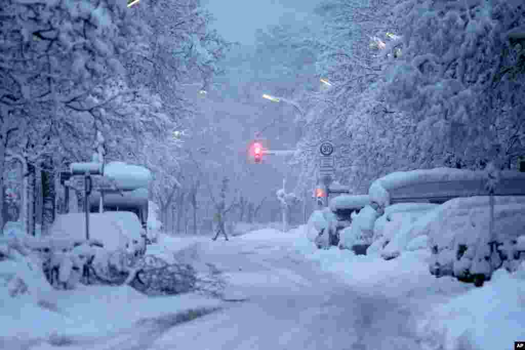 A man crosses a road early morning after heavy snow fall in Munich, Germany, Dec. 2, 2023.