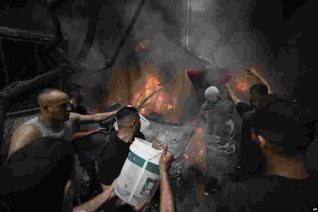 Palestinians extinguish flames engulfing a car after Israeli security forces raided the Balata refugee camp in the West Bank near the city of Nablus after their alleged failure to arrest a wanted militant in the heavily militarized camp.