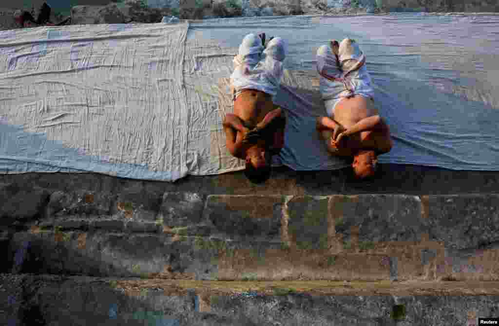 Devotees offer prayer by rolling on the ground during the month-long Swasthani Brata Katha festival at the bank of Hanumante river in Bhaktapur, Nepal.