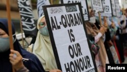 Seorang perempuan memegang poster bertuliskan, "Al-Qur'an adalah kehormatan kami" dalam aksi protes di depan kedutaan besar Swedia di Kuala Lumpur, Malaysia, pada 27 Januari 2023. (Foto: Reuters/Hasnoor Hussain)