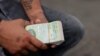 ARCHIVO - Hombre sostiene varios billetes de bolívares en Caracas, Venezuela, el 10 de abril de 2023.