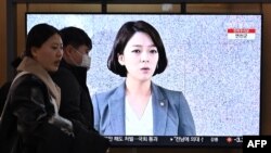 Orang-orang berjalan melewati layar televisi yang menayangkan siaran berita dengan rekaman file anggota parlemen dari Partai Kekuatan Rakyat Korea Selatan, Bae Hyun-jin, di sebuah stasiun kereta api di Seoul, 25 Januari 2024. (Jung Yeon-je/AFP)