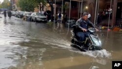 In this photo taken from video, a man drives a scooter through flood waters, Sept. 29, 2023, in the Brooklyn borough of New York.