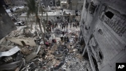 Palestinians look at the destruction after an Israeli strike in Khan Younis, Gaza Strip, Jan. 12, 2024. 
