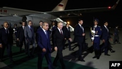 In this pool photograph by Russian state agency Sputnik, Russia's President Vladimir Putin (C-R) is welcomed by Azerbaijan's First Deputy Prime Minister Yaqub Eyyubov (C-L) upon his arrival at Heydar Aliyev International Airport in Baku, Aug. 18, 2024. 