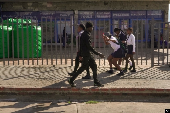 Three high school girls make their way through the city centre on their way to school in Dundee, South Africa, Friday, Oct. 27, 2023. (AP Photo/ Sebabatso Mosamo)