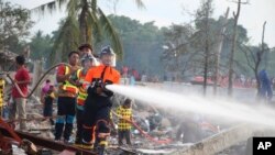 A fireman sprays water after an explosion occurred at a fireworks warehouse in Narathiwat province southern Thailand, July 29, 2023. At least nine people were killed, officials said.