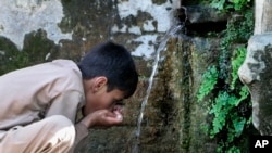 A boy drinks water from a line connected with a waterfall on the outskirts of Mingora, the main town of Pakistan's Swat valley, May 19, 2023.
