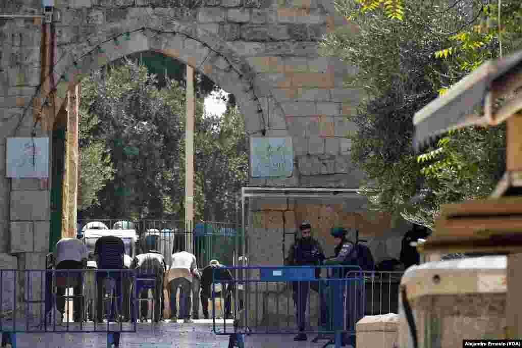 Hombres musulmanes rezan durante la oración del viernes en las afueras de la Explanada de las Mezquitas, fuertemente custodiada por la policía de fronteras de Israel.