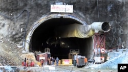 People stand near the entrance to the site of an under-construction road tunnel that collapsed in mountainous Uttarakhand state, India, Nov. 17, 2023. 