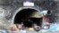 People stand near the entrance to the site of an under-construction road tunnel that collapsed in mountainous Uttarakhand state, India, Nov. 17, 2023. 